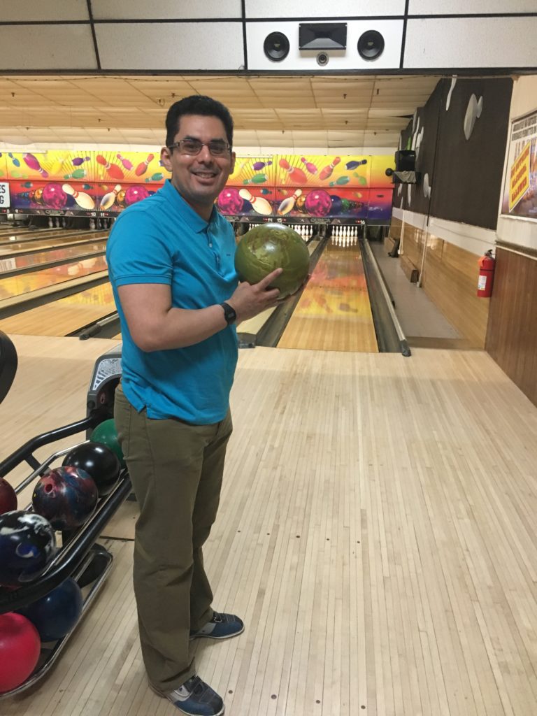 Image of an individual holding a bowling ball at a bowling lane.